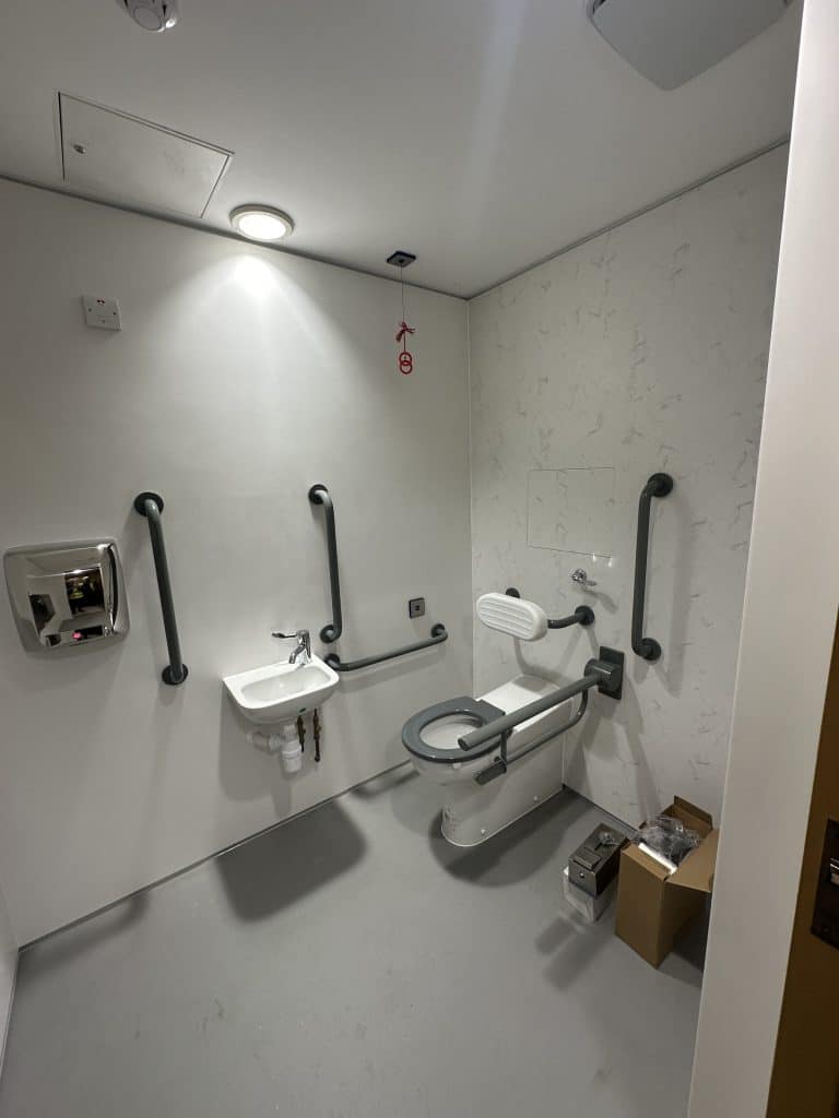 Accessible Washroom complete with Himacs Solid Surface wall cladding. IPS access panel in Himacs solid surface